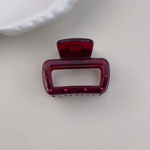Detail of dark burgundy rectangle hair claw clip with red polka dot studded accents
