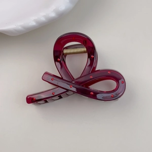 Close-up of a burgundy hair claw clip with red polka dots and a golden metal spring