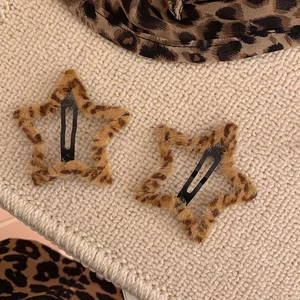 Détail de deux barrettes en forme d'étoile avec motif léopard sur un fond en tricot