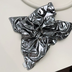 Detail of silver metallic scrunchie with shiny folded fabric and brand logo label