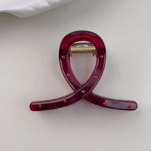 Macro detail of dark red translucent hair claw clip with red polka dots and gold spring