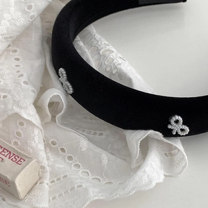 Elegant black velvet headband with white pearl bow on white lace background