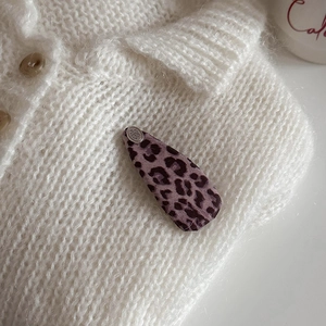 Detailed view of pink leopard print hair clip with silver metal charm on a knit sweater