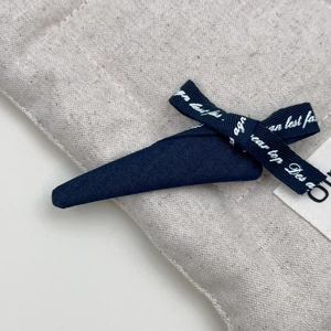 Detailansicht der blauen Denim-Schleife mit weißem Text auf strukturiertem Leinenstoff