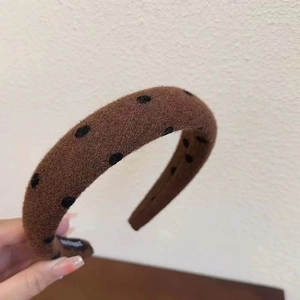 Detailed macro shot of handmade velvet headband with black polka dots and interior label