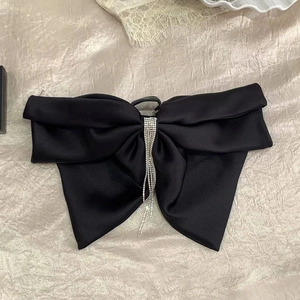 Détail d'une grande pince à cheveux en satin noir avec de longs glands en strass
