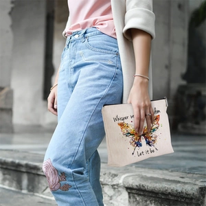 Detailed texture of linen makeup bag with colorful butterfly print and metal zipper closure