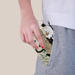 Portable canvas coin purse with cat print and keychain being placed in a pocket
