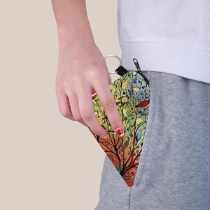 Artistic bird print canvas coin purse with metal keychain being tucked into a pocket