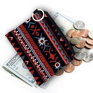 Detailed view of Aztec pattern coin purse with metal keyring over dollar bills and coins