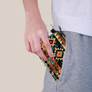 Aztec print coin purse with keychain being placed in a pocket for outdoor portability