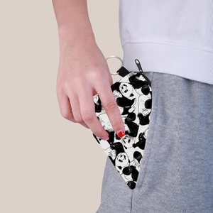 Portable panda print coin purse with keychain being placed into a pocket