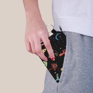Portable triangle coin purse with colorful mushroom prints being tucked into a pocket
