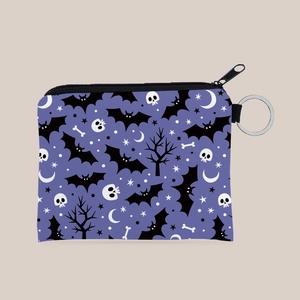 Detail of a purple Halloween coin purse with bat and skull patterns and metal keyring