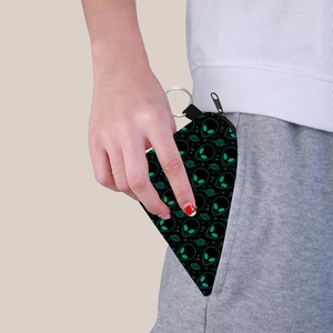 Portable alien print coin purse with keychain being tucked into a pocket