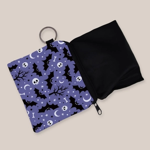 Detail of purple coin purse with black bat and skull patterns featuring a metal keychain