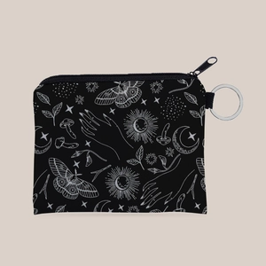 Close-up of bohemian coin purse with white mystic sun, moon and moth motifs on black fabric