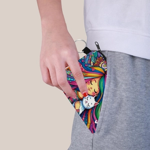 Detail view of cat and girl print coin purse being tucked into a pocket with metal keychain
