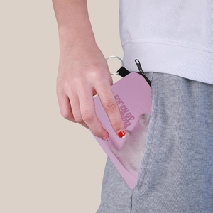 Pink fabric coin purse with cat print being tucked into a pocket for size reference