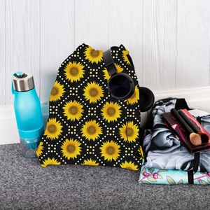 Detail view of sunflower drawstring bag with sports accessories on a white wooden background