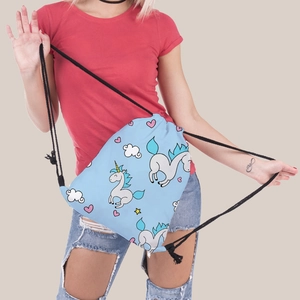 Detailed view of the drawstring backpack showing light blue unicorn print and black cords