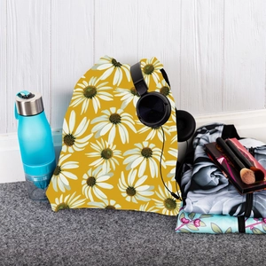 Detailed view of yellow drawstring backpack with white daisy floral print and travel items