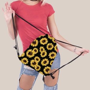 Close-up of bright sunflower pattern on black drawstring backpack held by model