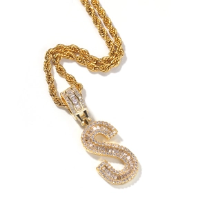 Close-up of gold letter S pendant necklace with baguette zircons and rope chain