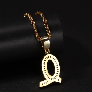 Macro shot of gold-plated letter Q pendant with black stones on a classic rope chain