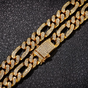 Close-up of gold iced-out Cuban link chain with diamonds on black leather background