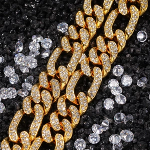 Macro detail of gold Cuban link chain with pave zircons on black textured sand background