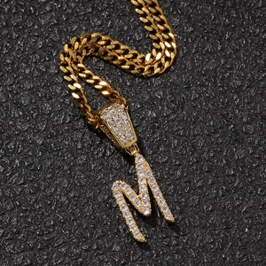 Macro shot of gold hip hop necklace featuring an iced-out letter M pendant with cubic zirconia