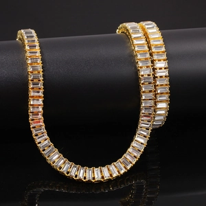 Macro shot of gold tennis chain with baguette cut cubic zirconia on a black stand