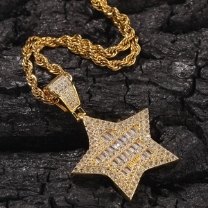 Detalle de colgante de estrella hip hop con circonitas de corte baguette y cadena de cuerda oro