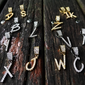 Hip hop style zircon encrusted letter pendants in gold and silver finishes on wood
