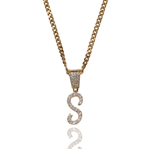 Detail view of iced out letter S pendant with gold Cuban chain in hip hop style