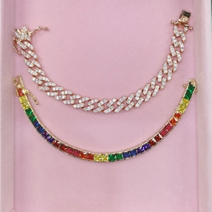 Detail of rose gold cuban link and rainbow gemstone tennis bracelet set on pink velvet