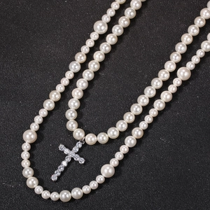 Primer plano de collar de perlas de doble capa con un colgante de cruz de circonitas