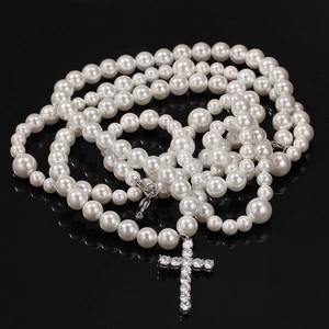 Detalle de collar de perlas de varias capas con colgante de cruz de circón sobre negro