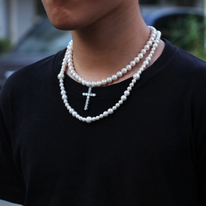 Detalle de collar de perlas de doble capa con colgante de cruz de circón en modelo masculino