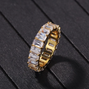 Detailed view of emerald cut zircon eternity ring in gold finish on wood texture
