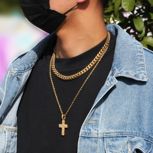 Détail de chaînes hip-hop dorées avec un pendentif croix en micro-pavé sur modèle