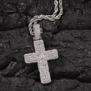 Vue macro du pendentif croix hip hop argenté avec zircons baguettes sur fond de charbon