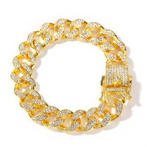 Macro detail of 13mm gold plated Cuban link bracelet with iced out crystals and fold-over clasp