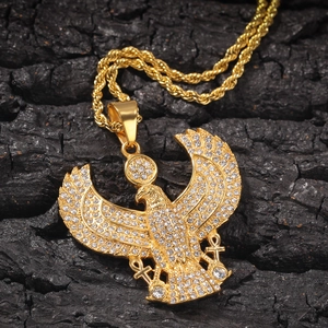 Macro shot of gold-plated Egyptian eagle pendant with white rhinestones on twisted rope chain