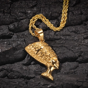 Macro du pendentif reine Néfertiti doré sur chaîne torsadée contre un fond de charbon noir