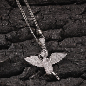 Macro shot of silver-toned angel pendant with sparkling cubic zirconia on dark stone