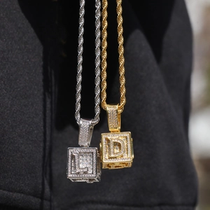 Vue rapprochée de pendentifs cubes hip hop or et argent avec zircons lettres D et L sertis