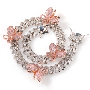 Detailed macro view of cuban link chain with rose gold butterfly and pink zircon inlay