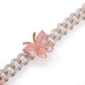 Macro shot of silver Cuban link chain with zircon micro-pave and rose gold butterfly